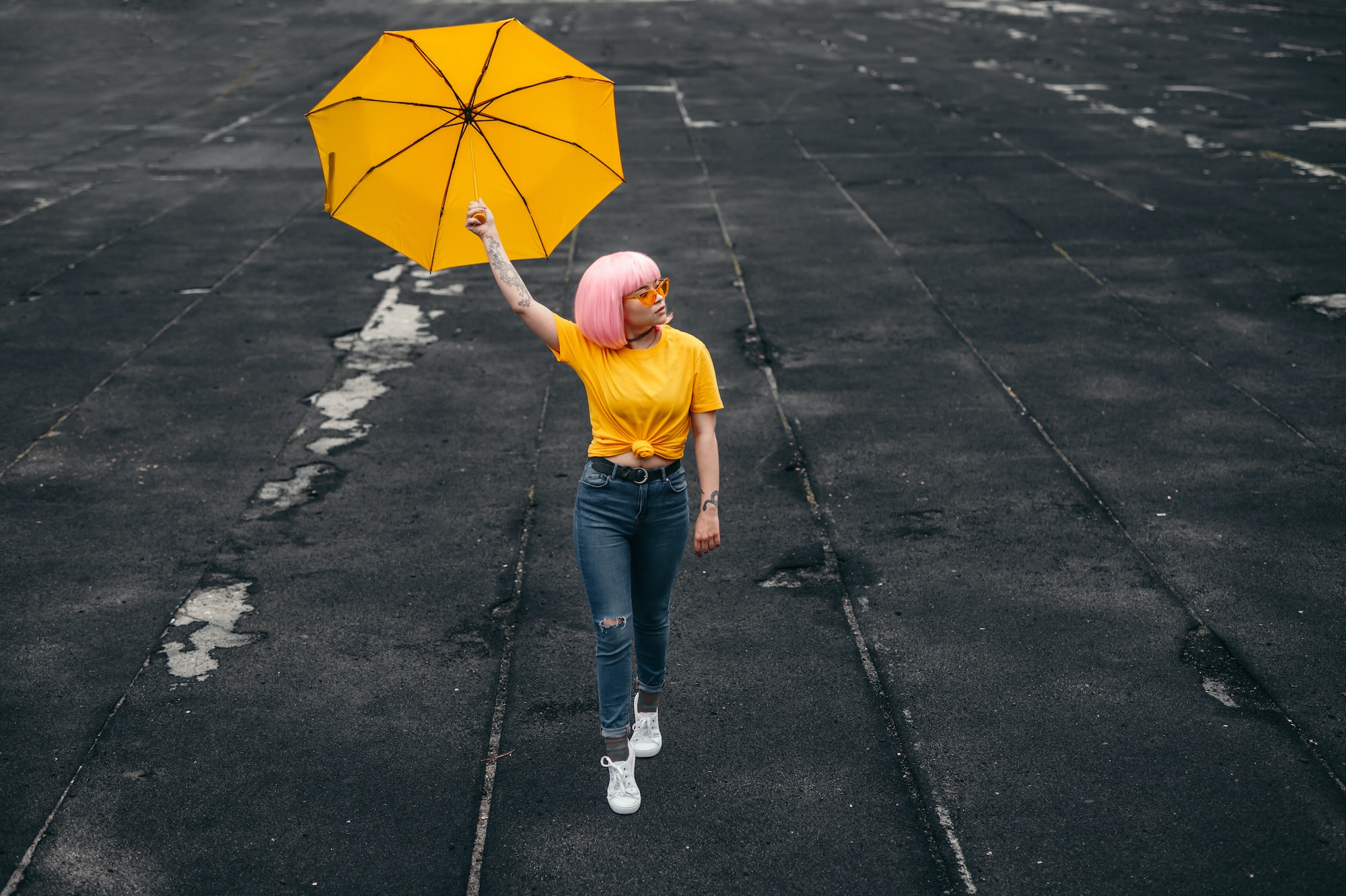 Teen influencer with yellow umbrella walking on street